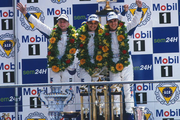 Allan McNish, Stéphane Ortelli, Laurent Aiello on the podium in front of a Mobil 1 logo at Le Mans in 1998