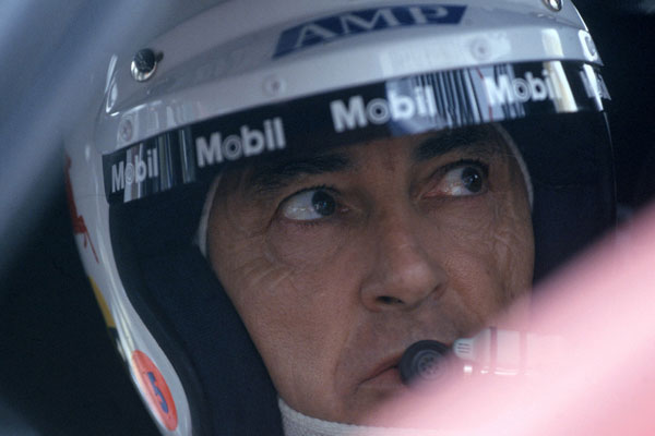 Peter Brock talking into a microphone wearing his helmet