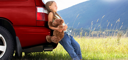 Child around the back of a car in the sun
