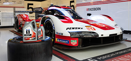 Porsche racing car in the garage with Mobil 1 bottle on a tire infront of the car