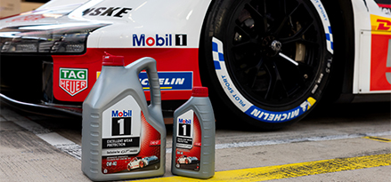 3 Porsche racing team members sat on a Porsche racing car