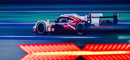 Red and white Porsche racing car on a track 