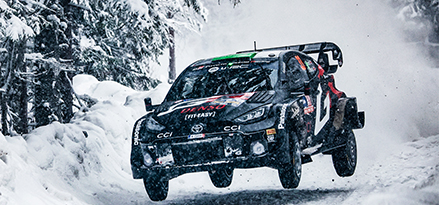 Toyota racing car driving through the snow in the air.