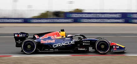 Single-seat Red Bull Oracle Formula 1 race car speeding along a racetrack, side view.